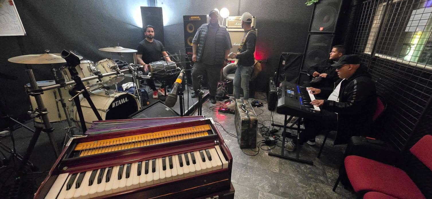 Overzicht van de oefenruimte met drumkit, harmonium en keyboard