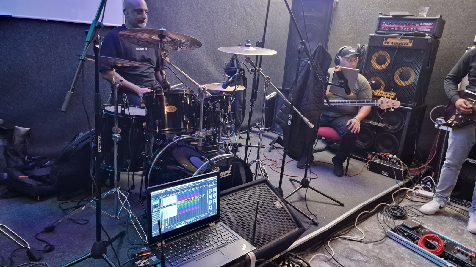 Band aan het repeteren in de oefenruimte met drums, bas en gitaar